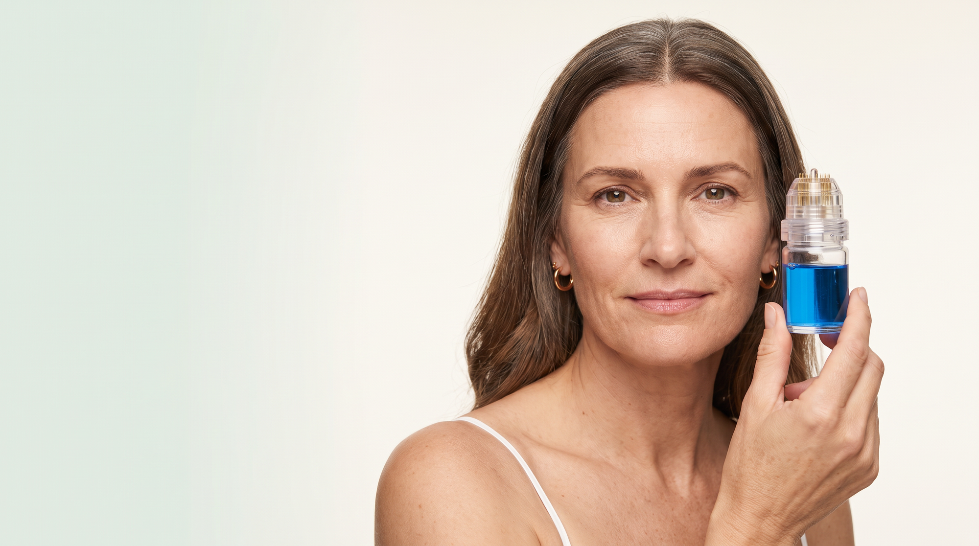 Woman in her fifties holding the Everlisse copper peptide applicator beside her temple
